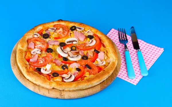 Aromatic pizza with fork and knife on blue background — Stock Photo, Image