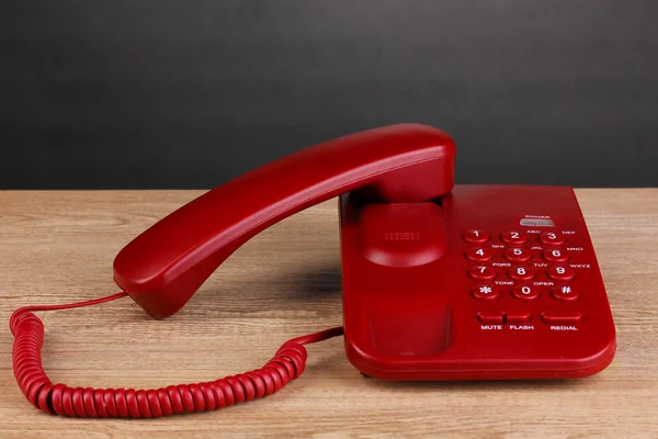 Röd telefon på träbord på grå bakgrund — Stockfoto