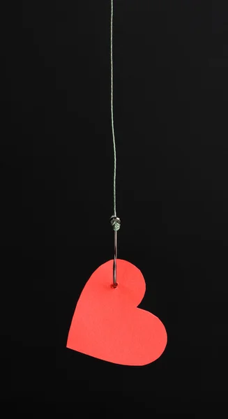 Heart on fish hook isolated on black — Stock Photo, Image