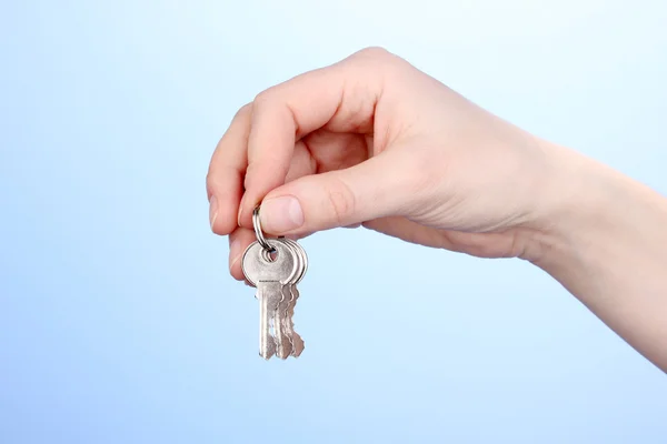 Key in hand on blue background — Stock Photo, Image