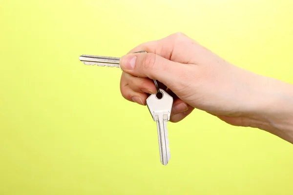 Keys in hand on green background — Stock Photo, Image