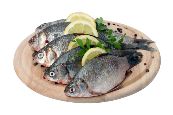 Fresh fishes with lemon, parsley and spice on wooden cutting board isolated on white — Stock Photo, Image