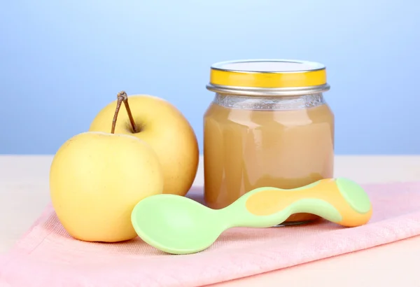 Jar of baby puree with spoon on napkin on blue background — Stock Photo, Image