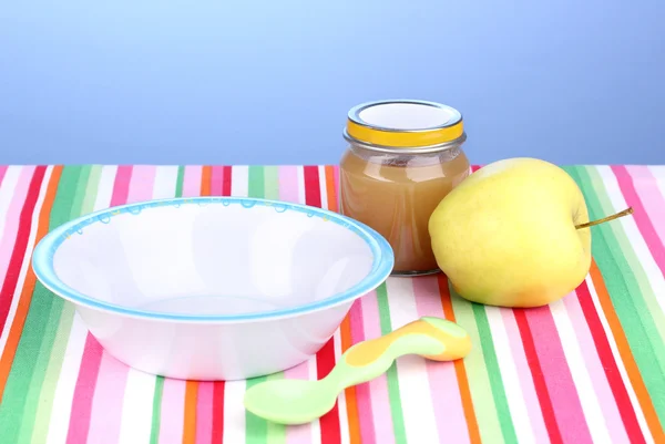 Vaso di purea di bambino con piatto e cucchiaio su tovagliolo su sfondo blu — Foto Stock