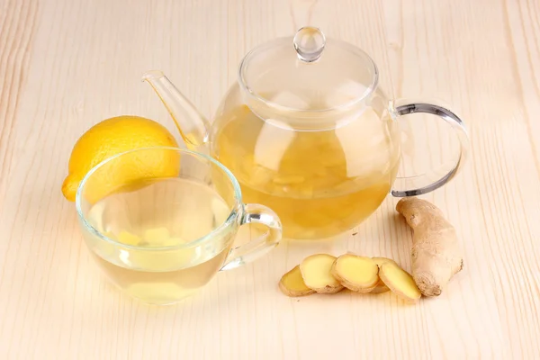 Tè allo zenzero sano in bollitore e tazza con limone su sfondo di legno — Foto Stock