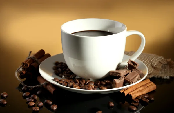 Secangkir kopi dan kacang-kacangan, tongkat kayu manis dan coklat di latar belakang coklat — Stok Foto