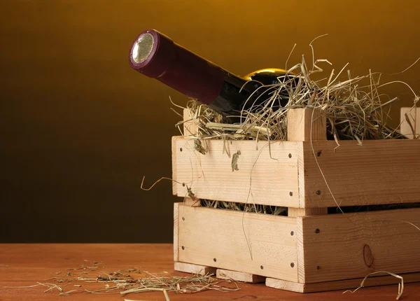 Botella de gran vino en caja sobre mesa de madera sobre fondo marrón — Foto de Stock