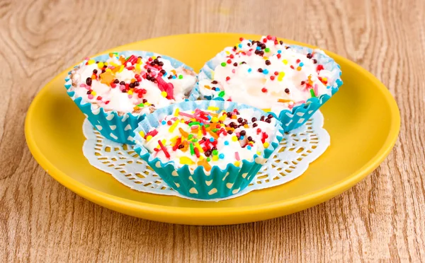Cremige Cupcakes auf Untertasse auf hölzernem Hintergrund — Stockfoto