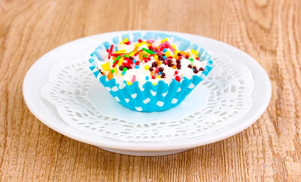 Cupcake cremoso su piattino su sfondo di legno — Foto Stock
