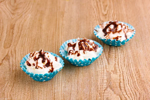 Cupcakes cremosos no fundo de madeira — Fotografia de Stock