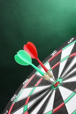 Dart board with darts on green background clipart