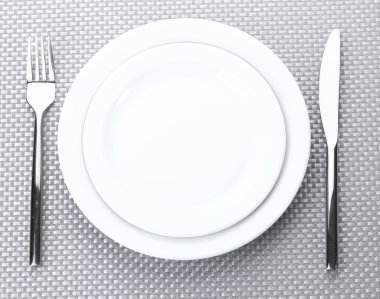 beyaz boş tabak çatal ve bıçak üzerinde gri bir masa örtüsü
