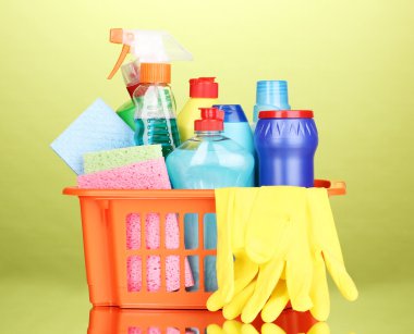 Basket with cleaning items on green background clipart