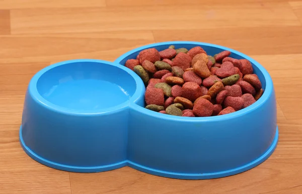 Comida de cão seco e água em tigela azul no chão — Fotografia de Stock
