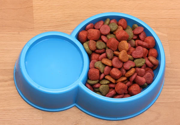 Сухой корм для собак и вода в голубой миске на полу — стоковое фото