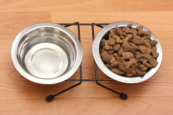 Comida cão seco e água em tigelas de metal no chão — Fotografia de Stock