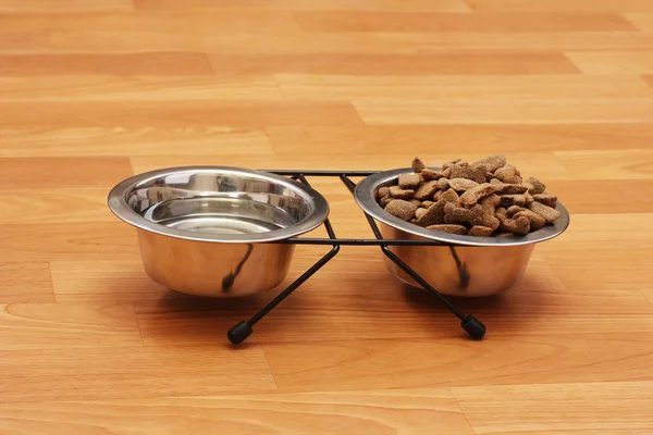 Pies suchej karmy i wody w metalowej miski na podłodze — Zdjęcie stockowe