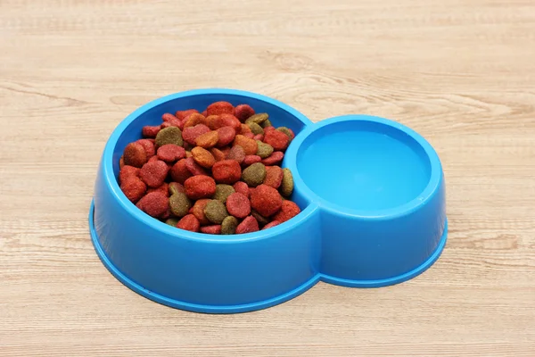 Comida seca para perros y agua en tazón azul sobre fondo de madera — Foto de Stock