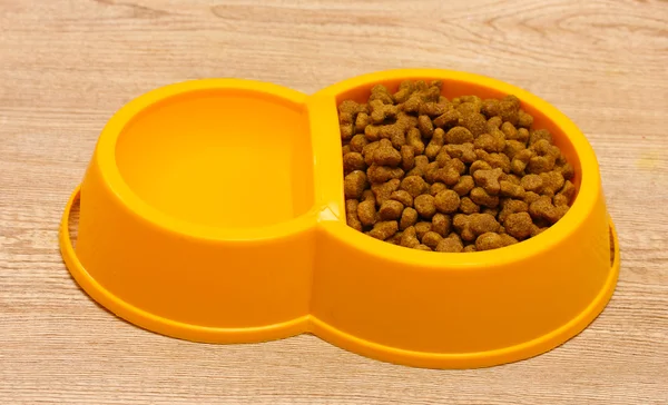 Torr kattmat och vatten i gul skål på trä bakgrund — Stockfoto
