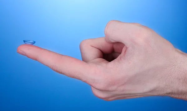 Lente de contato no dedo no fundo azul — Fotografia de Stock