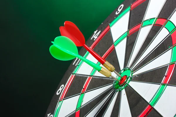 Dart board with darts on green background — Stock Photo, Image