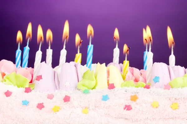 Verjaardagscake met kaarsen op violette achtergrond — Stockfoto