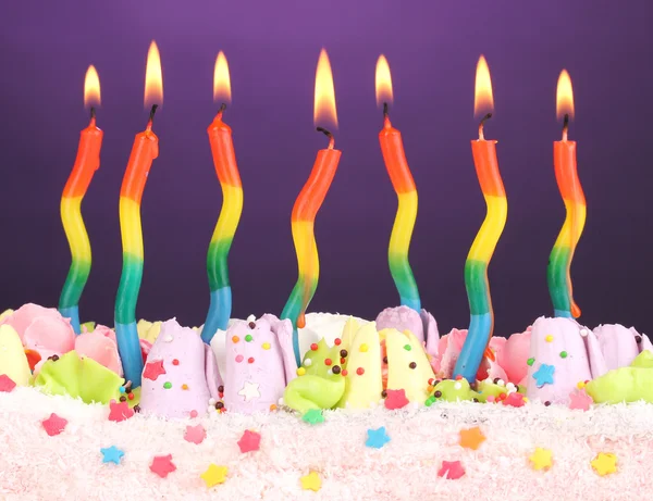 Tort urodzinowy z świece na fioletowym tle — Zdjęcie stockowe
