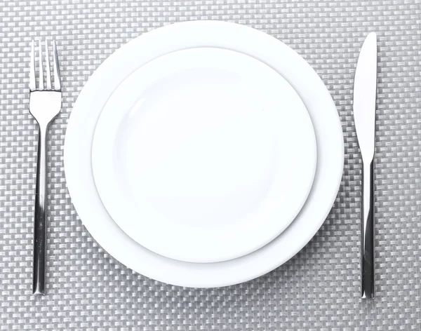 Beyaz boş tabak çatal ve bıçak üzerinde gri bir masa örtüsü — Stok fotoğraf