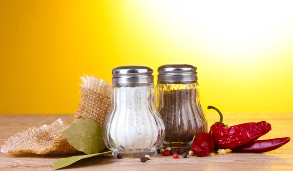 Salt och peppar mal och kryddor på träbord på gul bakgrund — Stockfoto