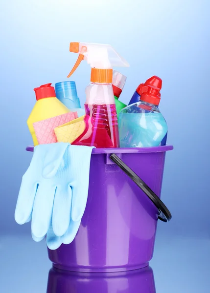 Balde com itens de limpeza em fundo azul — Fotografia de Stock