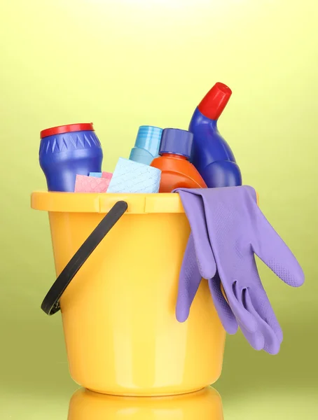 Bucket with cleaning items on green background — Stock Photo, Image