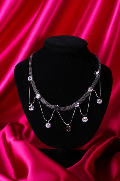 Krásný stříbrný náhrdelník na figurínu na červené hedvábné tkaniny — Stock fotografie
