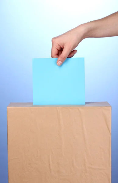 手の投票の投票用紙と青い背景上のボックス — ストック写真