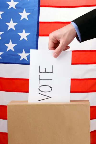 手の投票の投票用紙とアメリカ合衆国の旗にボックス — ストック写真
