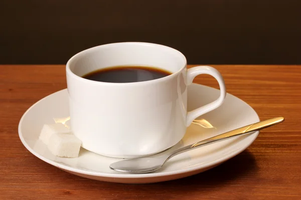 Šálek kávy na dřevěný stůl na hnědé pozadí — Stock fotografie