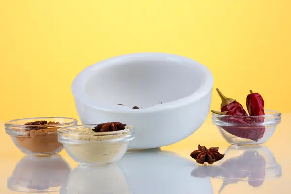 White mortar and pestle with spice on yellow background — Stock Photo, Image