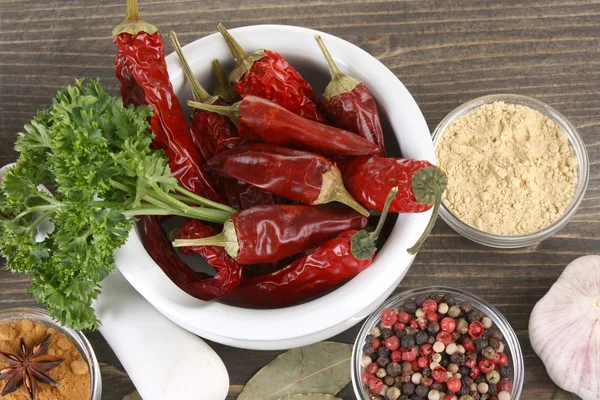 Composition of mortar with peppers and vegetables and spice on wooden background — Stock Photo, Image