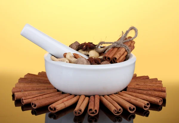 Composition of mortar with nuts and cinnamon on yellow background — Stock Photo, Image