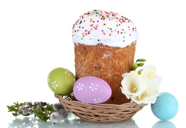 Hermosa tarta de Pascua en cesta, huevos coloridos y flores aisladas en blanco — Foto de Stock