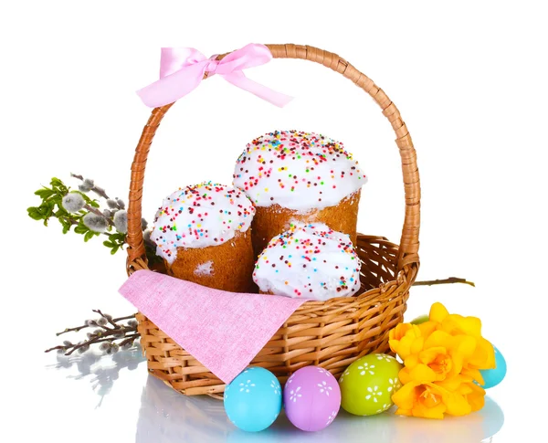 Красивые пасхальные торты в корзине, красочные яйца и цветы изолированы на белом — стоковое фото