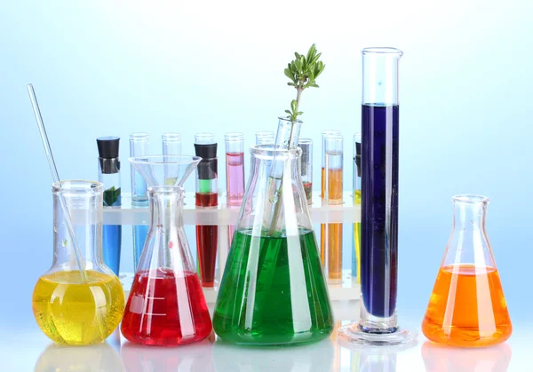 Forskellige laboratorieglas med farve væske på blå baggrund - Stock-foto