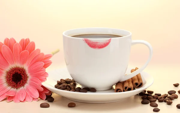 Kopp kaffe med läppstift mark och gerbera bönor, kanel pinnar på träbord — Stockfoto