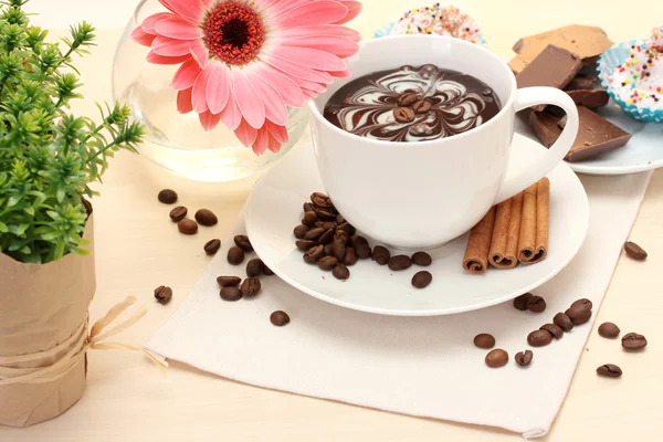 Cup of coffee and gerbera beans, cinnamon sticks on wooden table — Stock Photo, Image