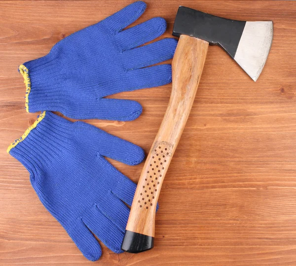 Ascia e guanti su sfondo di legno — Foto Stock