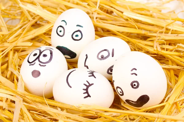 Bílá vejce s ksichty v slámy — Stock fotografie