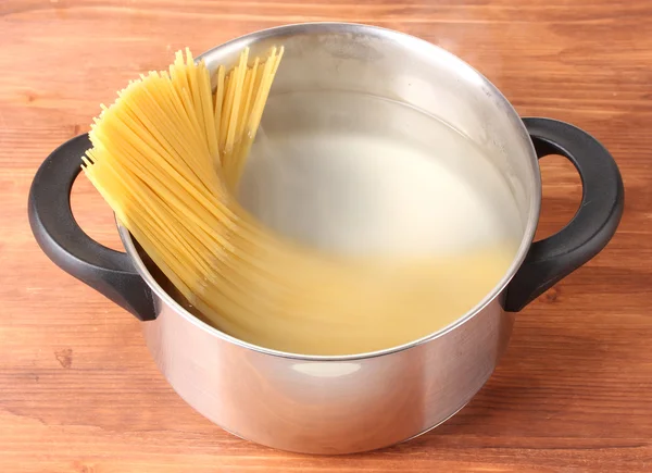 Готувати спагетті на сковороді на дерев'яному фоні крупним планом — стокове фото