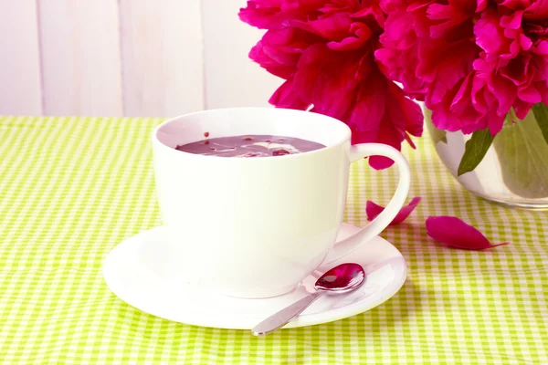 Xícara de chocolate quente e flores na mesa no café — Fotografia de Stock