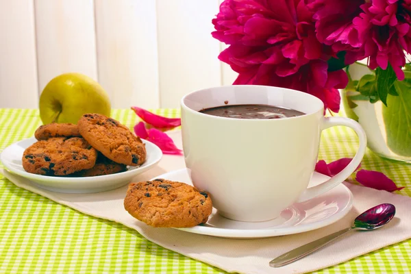 Φλιτζάνι ζεστή σοκολάτα, μήλο, μπισκότα και λουλούδια στο τραπέζι στο café — Φωτογραφία Αρχείου