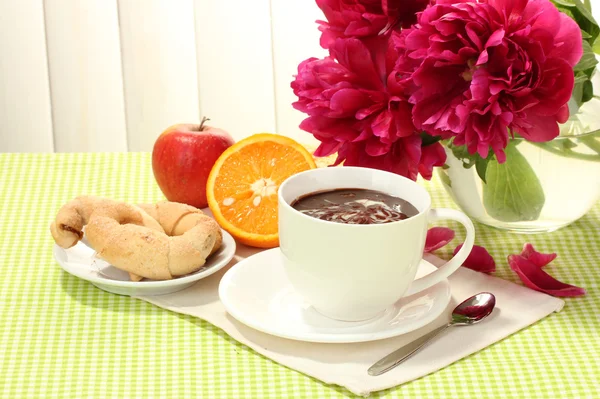Xícara de chocolate quente, maçã, laranja, biscoitos e flores na mesa no café — Fotografia de Stock