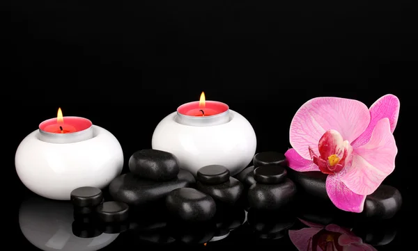 Pedras de spa com flor de orquídea e velas isoladas em preto — Fotografia de Stock